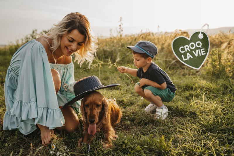Mère et fils dans la nature heureux avec leur chien ayant résolu ses problèmes de grattements depuis qu'il mange les croquettes CROQ' la Vie