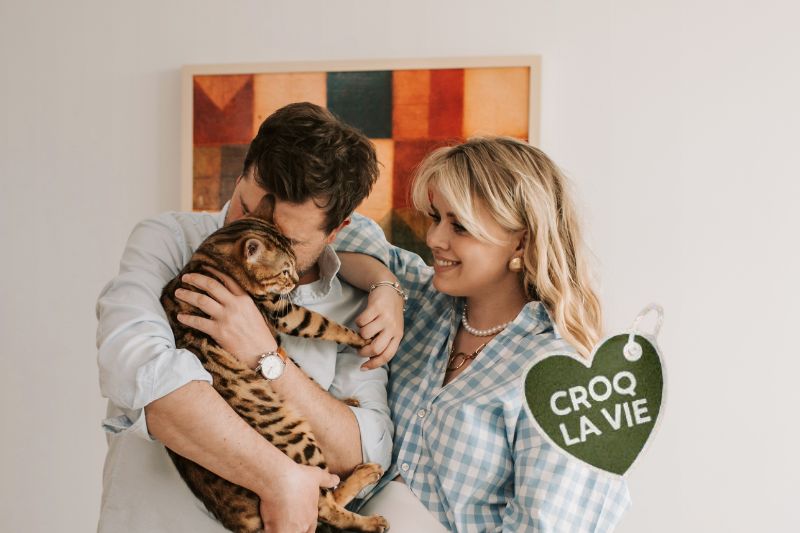 Couple fait des calins à son chat heureux ayant résolu les problèmes de'Insuffisance rénale de son chat depuis qu'il mange les croquettes CROQ'la Vie