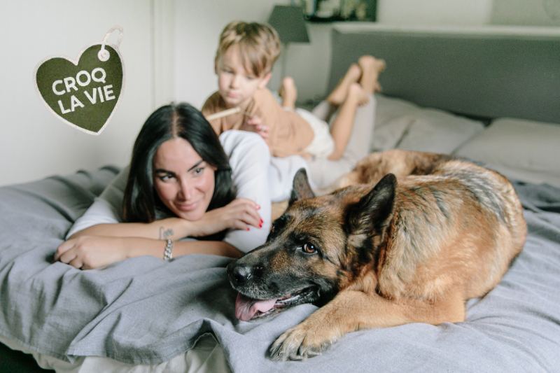 Mère et fils font des câlins à leur chien, heureux d'avoir résolu les problèmes de diarhée avec des glaires de leur chien. Le chien est un pleine santé grâce aux conseils d'éleveurs et aux croquettes CROQ' la Vie.