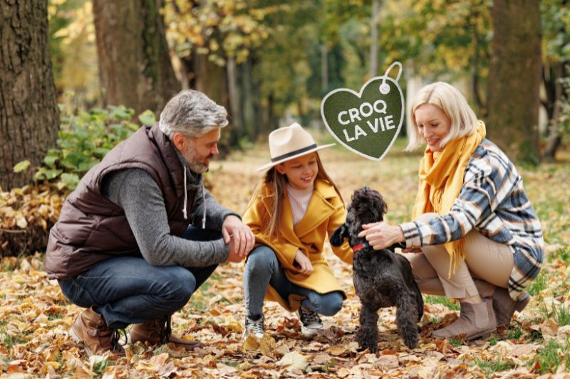 Famille fait des câlins à son chien, heureuse d'avoir amélioré sa santé urinaire de manière naturelle. Le chien est un pleine santé grâce aux conseils d'éleveurs et aux croquettes CROQ' la Vie.